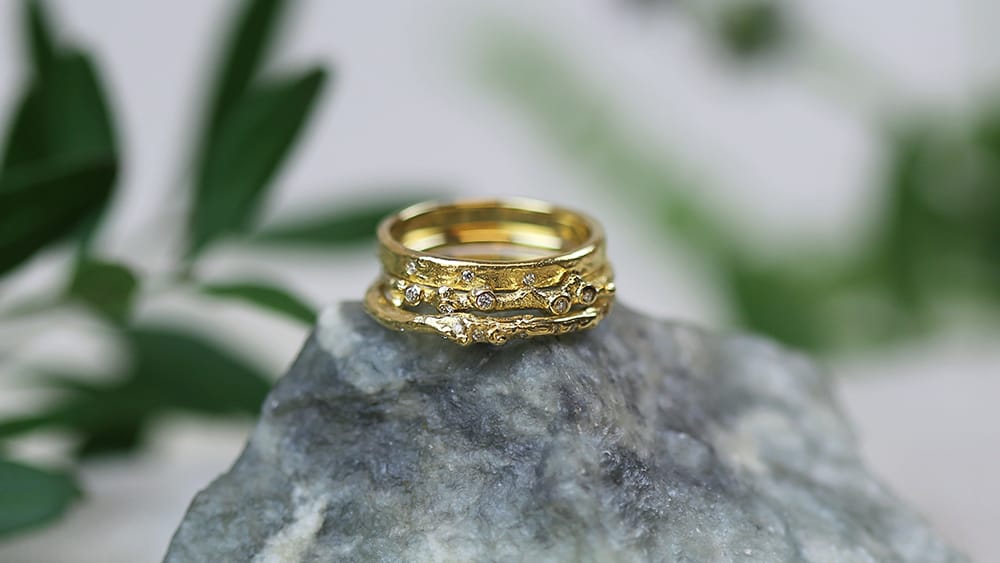 Three textured solid gold wedding bands, with diamonds.